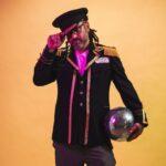 Man in captain's jacket holding a disco ball at side in a photo studio