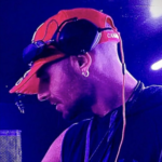 Man in red baseball cap with headphones and a thick earing
