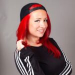 Woman with red hair and a backwards baseball cap 
