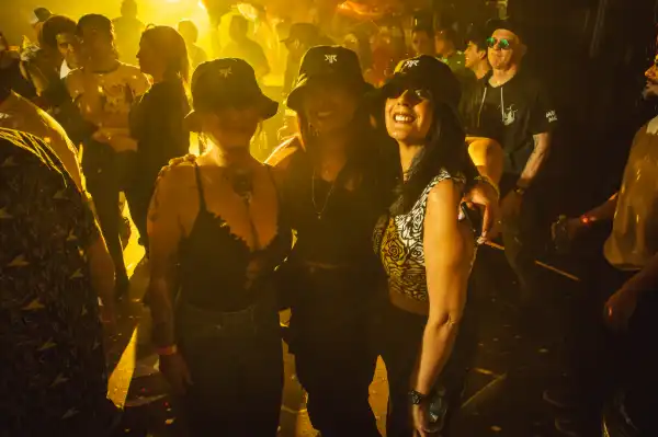 Three women on dancefloor in yellow light