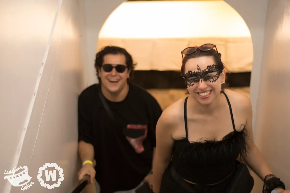Couple in masks smiling on stairs at a party