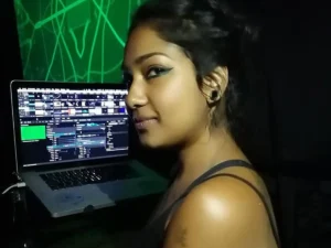 Woman with headphones at DJ booth with laptop and green screen
