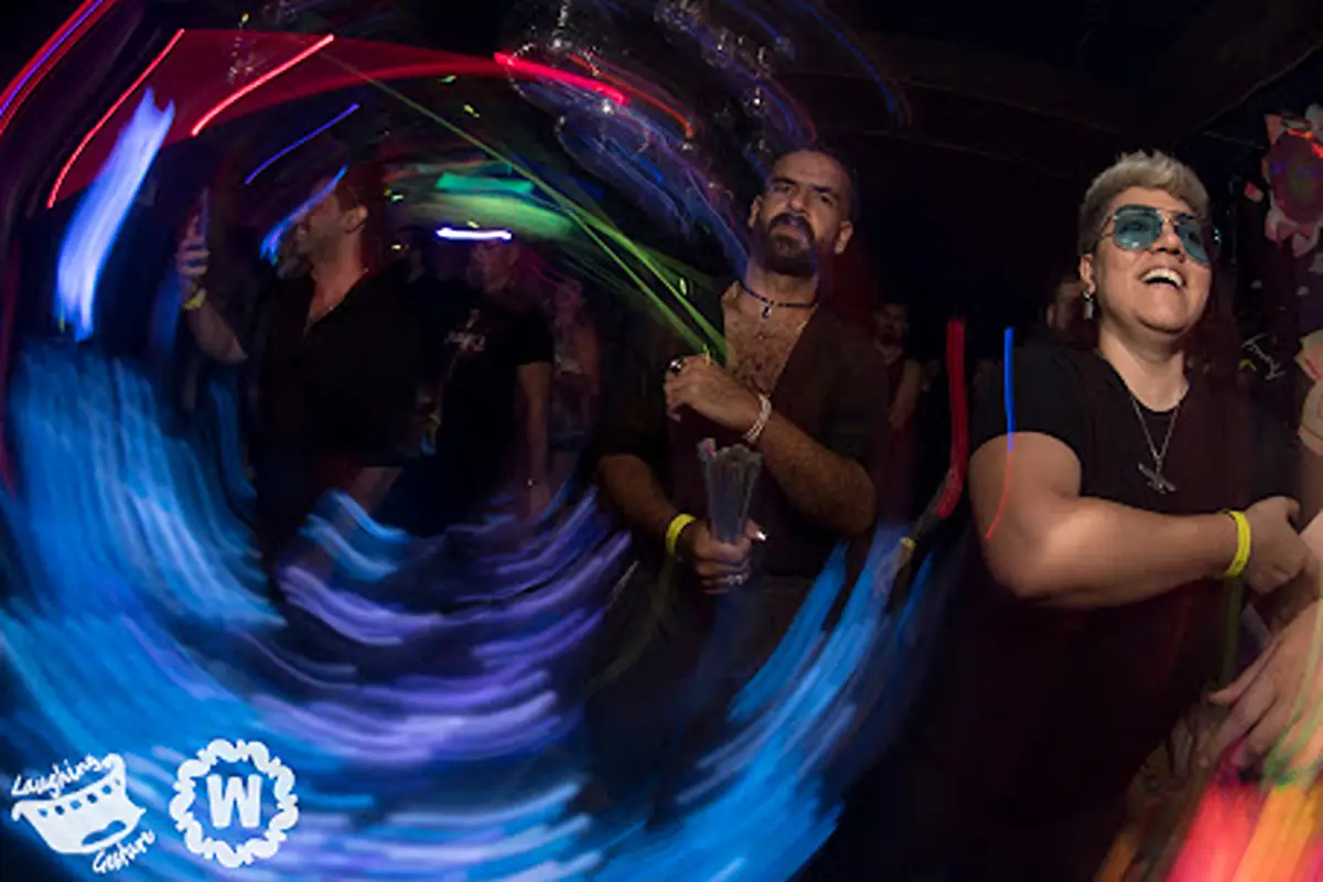 People dancing at a club with colorful lights and motion blur.