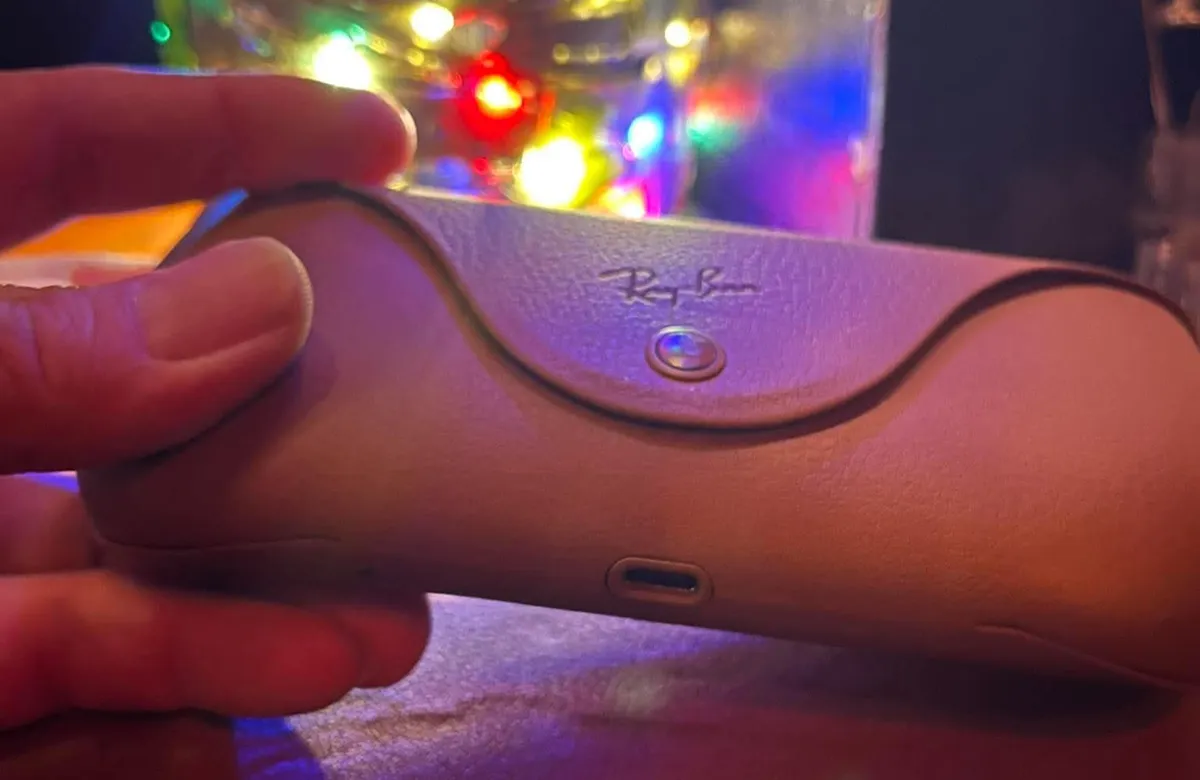 Ray-Ban sunglasses case with USB-C port and colorful lights in background