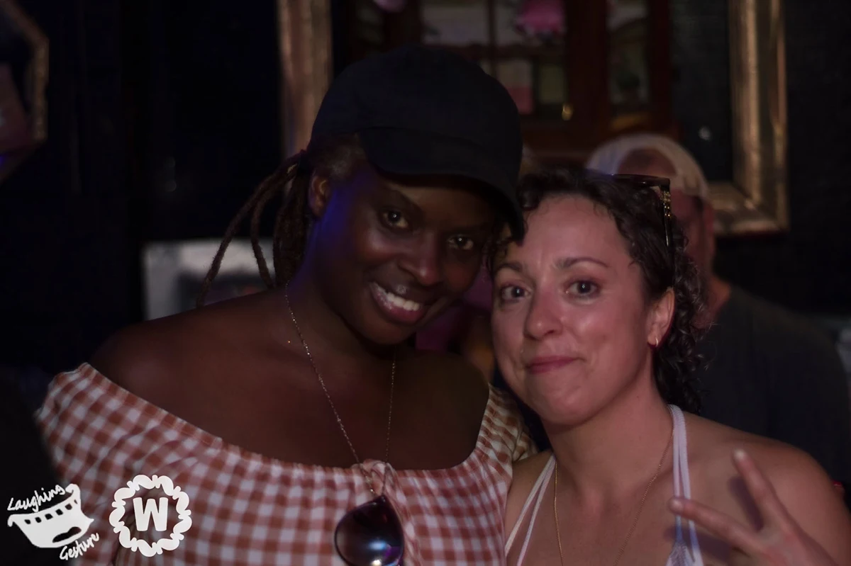 Two women posing for a photo, one wearing a black cap and plaid top.